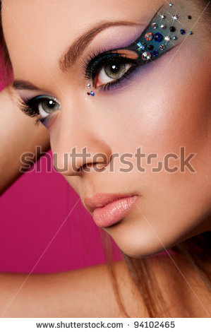 pretty brunette woman with creative makeup on pink background - stock photo