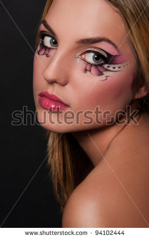 pretty brunette woman with creative makeup on black background - stock photo