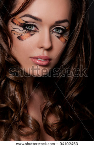 pretty brunette woman with creative makeup on black background - stock photo