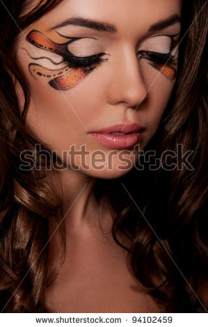 pretty brunette woman with creative makeup on black background - stock photo