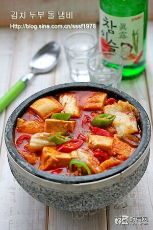 韩式辣白菜豆腐汤材料；南豆腐，辣白菜。青尖椒红尖椒，做法； 1.豆腐过水冲洗一下，分切成正方小块  2.辣白菜切成小片  3.青红尖椒斜切成圈  4.石锅置于火上，锅底倒少量油，中火加热  5.油温八成热时，下入青红椒圈扒炒一下  6.然后下入辣白菜，翻拌扒炒均匀  7.加入韩式辣椒酱  8.加入半锅水，搅拌均匀  9.待到汤汁煮至沸腾时，下入豆腐块  10.拌匀后煮至再次沸腾时改小火，炖煮10分钟左右即可，最后加少量鸡精调味，即可关火