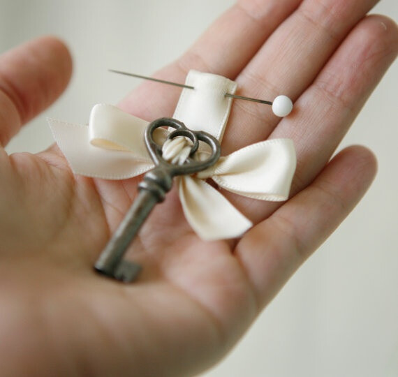 Instead of a boutonniere the groom wears a key and the bride has the lock to it on her bouquet.