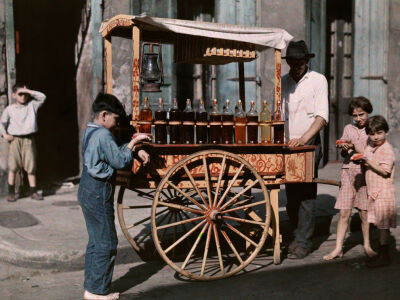 Children gather around a French Quarter snowball wagon in this Autochrome image originally published in the April 1930 issue of National Geographic. "These are the only 'snowballs' the children of New…