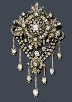 DIAMOND BROOCH, ca. 1880. Silver over pink gold. Fancy, florally open-worked brooch with circle, bow, palmette and leaf motifs, and 5 pendants with old European cut diamonds as the lower part. Below, …