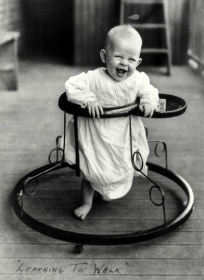 Learning to Walk - A joyful baby takes a spin in a walker in 1905.