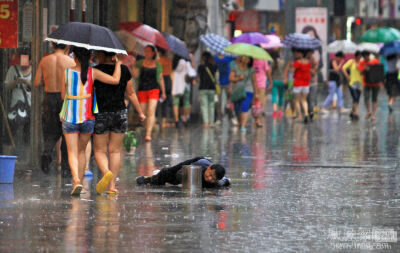 2013年6月26日，江西九江大中路步行街上，一名腿部残疾的乞讨者缓慢地爬行着。