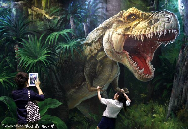 泰国纯武里府芭提雅市的天堂博物馆里，一名泰国游客正在与一幅3D图画合影，照片中的女游客仿佛用手抓住一只真正的恐龙。