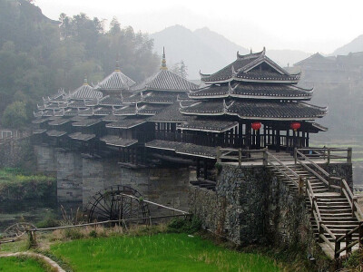 中国三江县：程阳风雨桥——横跨林溪河，是一座木石结构的大桥，建于1916年，桥上建有5座塔式桥亭，飞檐高翘。桥上的壁柱和瓦檐上雕刻着精细复杂的绘画，富丽堂皇。程阳桥中间有一块大理石碑，上面刻着中国著名历史…