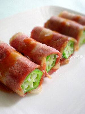 【秋葵培根卷】  做法：  1、秋葵洗净去头尾改刀成寸段，入沸水中汆烫2分钟捞出；  2、培根对半切开（一长条可卷两段秋葵），放入平底锅（不用放油）小火略煎至熟，将秋葵段卷起摆盘，淋上甜辣酱即可