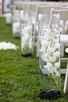 The ceremony aisle will feature varying heights of cylinder vases with submerged white tulips, white stock flowers, and ivory spray roses.