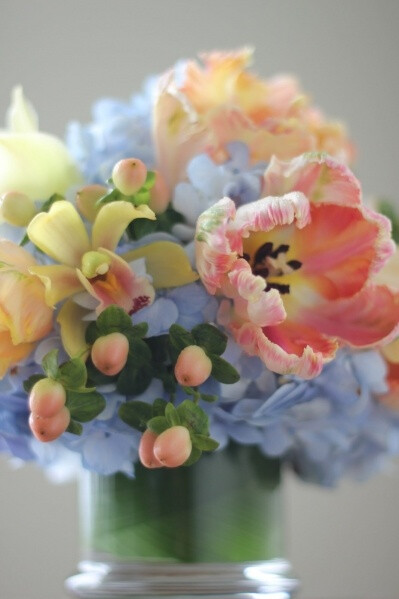 tulip and orchid, hydrangea or delphinium in a peach, yellow, and blue flower arrangement