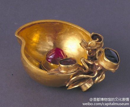 嵌宝石桃形金杯：明，高4.4厘米 长6.8厘米 宽5.2厘米，北京永定门外南苑万通墓出土。杯体为剖开的半个桃子形，杯柄为桃枝与桃叶，杯中与柄部镶嵌红、蓝宝石。此杯将红宝石的鲜红、蓝宝石的深蓝与黄金本身的金黄三者合于一体，使本来因缺少纹样装饰而显得单调的器物增添了富丽的效果。