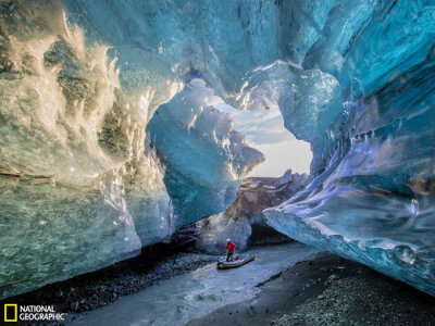 【 国家地理：二月最佳旅行图片赏】一位筏夫在冰岛瓦特纳冰川下方漂流。冰岛位于活跃的大西洋中脊之上。北美和欧洲板块在此撕裂，形成了一个巨大的活火山带。