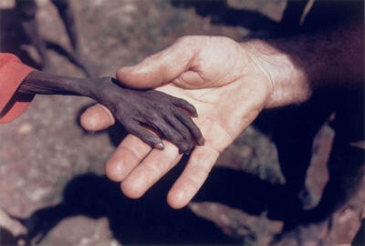 16】1980年，乌干达卡拉莫贾地区，一名传教士握着一个骨瘦如柴的小男孩的小手。