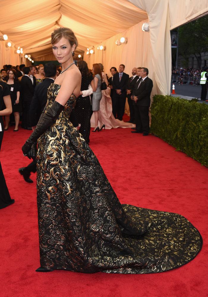 KARLIE KLOSS in Oscar de la Renta Glamorous in gilded brocade Karlie dazzles in Oscar de la Renta’s shimmering gown. With a flowing train and black leather gloves, Karlie’s look is dramatic, yet still in line with the retro Charles James look.