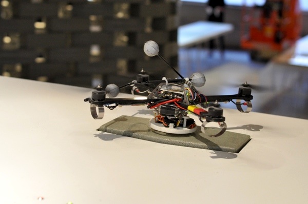 Four quadrocopters perched on their recharging stations, high above the audience.