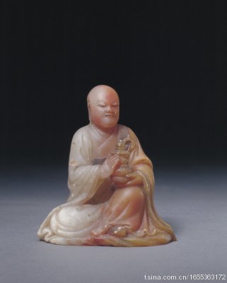 “玉璇”款寿山石雕罗汉像：“玉璇”款寿山石雕罗汉像，宽5.5cm，高7cm。 罗汉内著交领衣，外披袈裟，双手端捧宝塔，神态安详。发式、衣饰雕刻精美，背后镌有“玉璇”款，为清代雕刻名家杨玉璇的代表作品，具有…