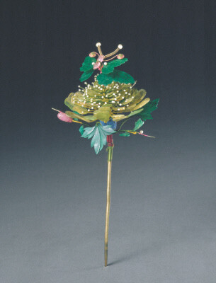 镶宝石碧玺花簪，清乾隆，长25cm，宽12cm。 花簪为铜镀金点翠，上嵌碧玺、珍珠、翡翠。以碧玺做立体芙蓉花，花蕊为细小米珠，花叶为翡翠薄片细雕而成，花蕾为碧玺雕成，花托为点翠。一只蝴蝶停落于芙蓉花上，其翅膀…