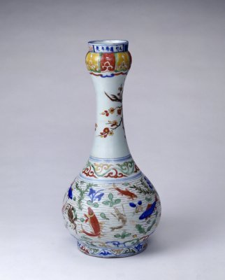 五彩鱼藻纹蒜头瓶，明万历，高40.3cm，口径7.8cm，足径13.7cm。 瓶蒜头口，细长颈，圆腹下垂，圈足。通体青花五彩装饰，釉上彩有红、黄、绿、褐、紫彩等。腹部绘鱼藻纹，颈部绘折枝梅花纹。上下衬以变形莲瓣、…