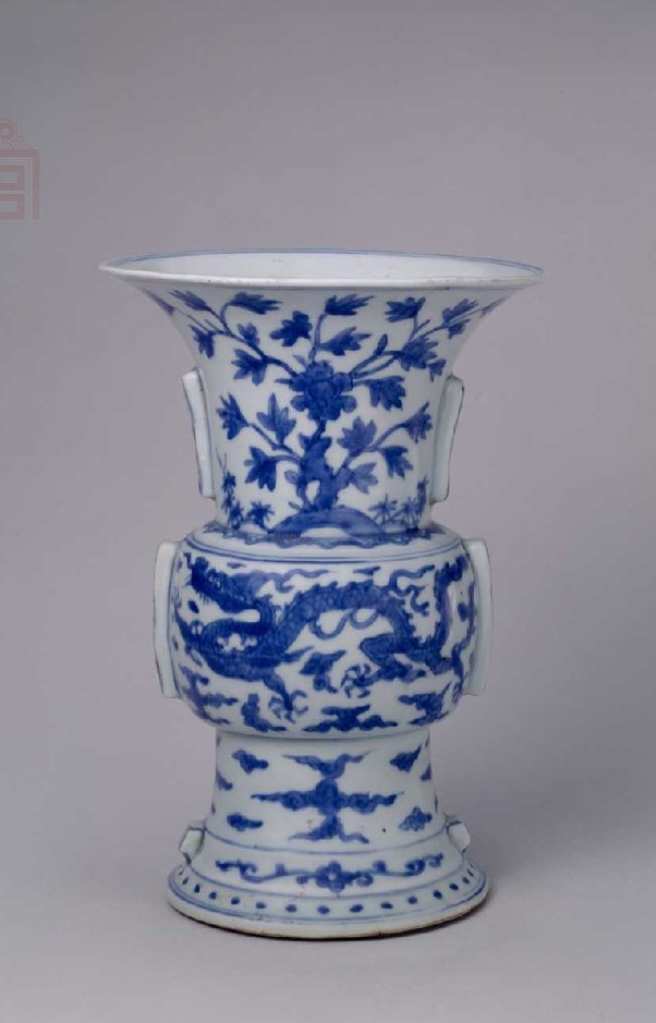 明万历 青花龙凤纹出戟花觚，明万历，高21.9cm，口径15.7cm，足径11.3cm。 觚（gū 音孤）撇口，长颈，鼓腹，两侧对应出戟（jǐ 音几），高圈足外撇。通体青花装饰。腹部主题图案绘云龙和云凤纹。颈部绘洞石牡丹两组。足上绘云朵、折枝花和圆点纹。圈足内施白釉。外底署青花楷体“大明万历年制” 双行六字款，外围青花双线圈。 此觚为宫廷陈设用器，仿商周青铜器式样，造型端庄，雄浑古朴。青花呈色蓝中泛紫。图案寓意吉祥，龙凤纹组合描绘寓意“龙凤呈祥”。