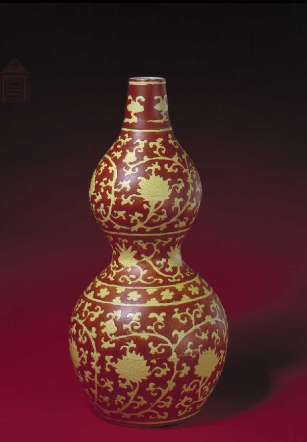 明嘉靖   黄地红彩缠枝莲纹葫芦瓶，高45.1cm，口径5.1cm，足径13.4cm。 瓶为葫芦形，上小下大，直口，溜肩，束腰，双鼓腹，圈足。通体黄釉红彩划花装饰，口部为朵云纹，上下二段主题纹饰绘缠枝莲花，上为四朵，下为二朵，束腰处绘缠枝灵芝纹。自上至下有六道弦纹，把纹饰分为五层。其作法是先烧成黄釉暗花，然后用矾红彩涂色地，托出黄色的主题花纹，色调对比艳丽。这种“黄上红”技法为嘉靖时期专用，后世少有仿作。此瓶足内白地青花双圈内书“大明嘉靖年制”六字款。