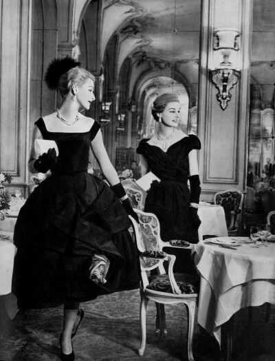 Models in cocktail dresses, on the left Fath's draped silk caught by red rose and right Patou's black taffeta, jewelry by Van Cleef &amp;amp; Arpels, photo by Georges Saad at the Ritz restaurant, Pari…
