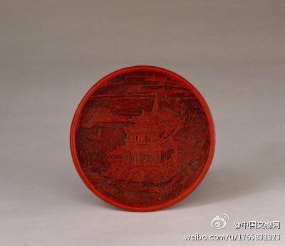 剔红岳阳楼图圆盘】明，高2.4cm，口径17.7cm。盘圆形，漫浅式。盘内以天、水细锦为地，雕刻出一幅优美的山水人物图。空中彩云如带，崇阁矗立，阁内众多人物各有所事，阁下临江，江中水波荡漾，舟船乘风行驶，场景热闹生动。盘外壁雕花卉纹，足内髹黑漆，无款识。