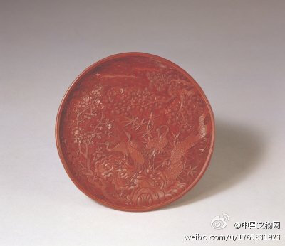 剔红松竹梅鹤纹圆盘】明嘉靖，此为三盘成套，大小递减，高2.2cm，2.2cm，1.6cm，口径26.2cm，20.2cm，17.3cm。盘圆形，漫浅式，涡纹边。盘心雕天、水、地三种锦纹为地，上压松竹梅、仙鹤图案。最小的盘足内正中刻“…