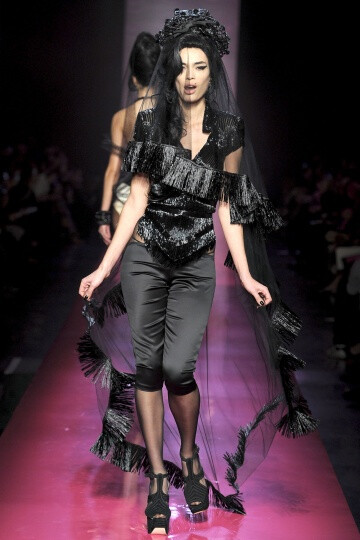 Jean Paul Gaultier SS2012 Couture。Gaultier 成功地将他的高级时装发布变成了Amy Winehouse的欢送会，并为他美丽而怪异的服装增添了色彩艳丽的一笔。并且Gaultier 设计的用披肩包住一边的细条纹西装夹克、珠饰细腿…