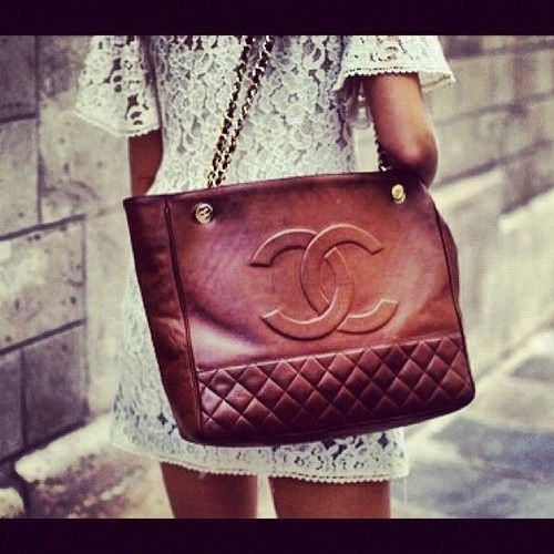 A brown rust color tote chanel bag. With gold chain handles. Large signature chanel embroidered on the tote