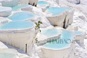 进入棉花堡温泉池(Pamukkale Thermal Pools)要先赤脚行进250米才能到达上方平台，玉一样的半圆形白色天然阶梯层层叠叠，犹如雪砌的梯田，远看像大朵大朵的棉花矗立在山丘上，无数涓涓细流从丘岩间的缝隙潺潺流下，温热的水蒸气让棉花堡氤氲在淡淡的缥缈雾气里，泉水积在台阶之间，形成一汪汪波澜不兴的水池，这便是有世界七…