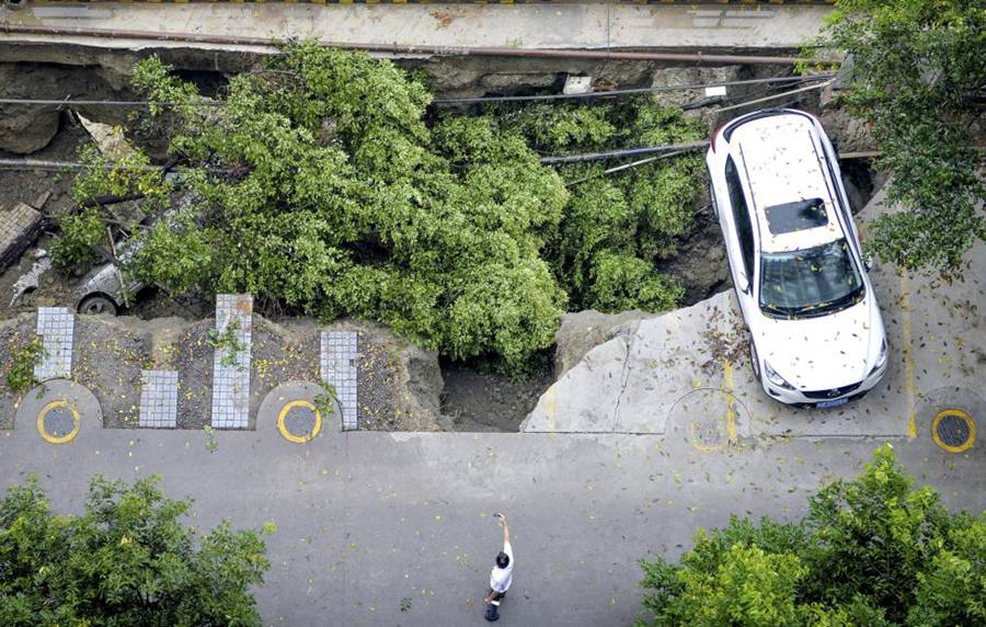 7月9日，中国四川省成都市，连日大雨过后，路面塌陷，吞噬了汽车和树木。