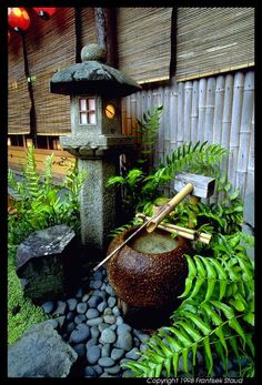 This hits almost all of our we-love-Japanese-gardens buttons. It's got the cool stone lantern, the rustic stone water well, a beautiful old rock, river rocks, and simple ferns to add softness and gree…