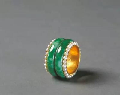 金嵌翠戒指，清，直径2.2厘米。 此戒指内部为金里，由薄金片制成，其外嵌翠环两周，素无纹饰，有天然的绿色纹理。戒指两圈口处各嵌珍珠一周。