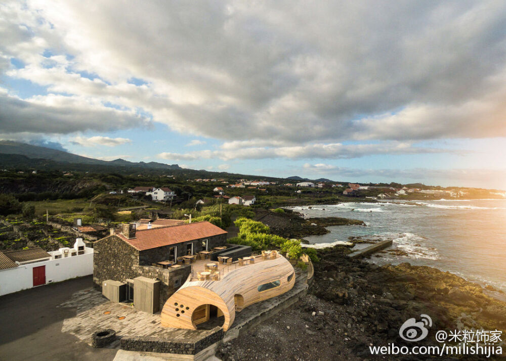 餐厅扩建是不少建筑事务所面临的课题，这家位于葡萄牙亚速尔群岛（ Azores ）中的皮库(Pico)岛上带酒吧的餐厅，原本只有一个火山岩墙面的老房子，来自葡萄牙的 FCC 建筑事务所的设计师直接在外面加了一个木……桶。