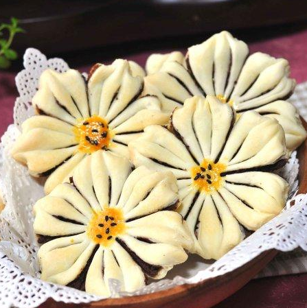 【豆沙葵花酥的做法】 先做豆沙馅： 材料：红豆300g，花生油60g，白砂糖60g 做法： 1、红豆提前清水浸泡，泡涨、泡透，最好过夜；上火煮至熟烂。 2、用料理机打成泥，加入糖和油。 3、继续上火，小火慢慢煸炒至适当的干湿度。 做面皮材料： 水油皮：低筋面粉150g，细砂糖30g，黄油30g，水60g 油酥皮：低筋面粉100g，黄油50g 馅料：豆沙馅适量，装饰：蛋黄液，黑芝麻 做法： 1、水油皮的面粉、糖和黄油搓成粗粉，在加入水。 2、和成均匀的水油皮面团，混合油酥皮的粉和油。 3、和成均匀的油酥皮面.团。