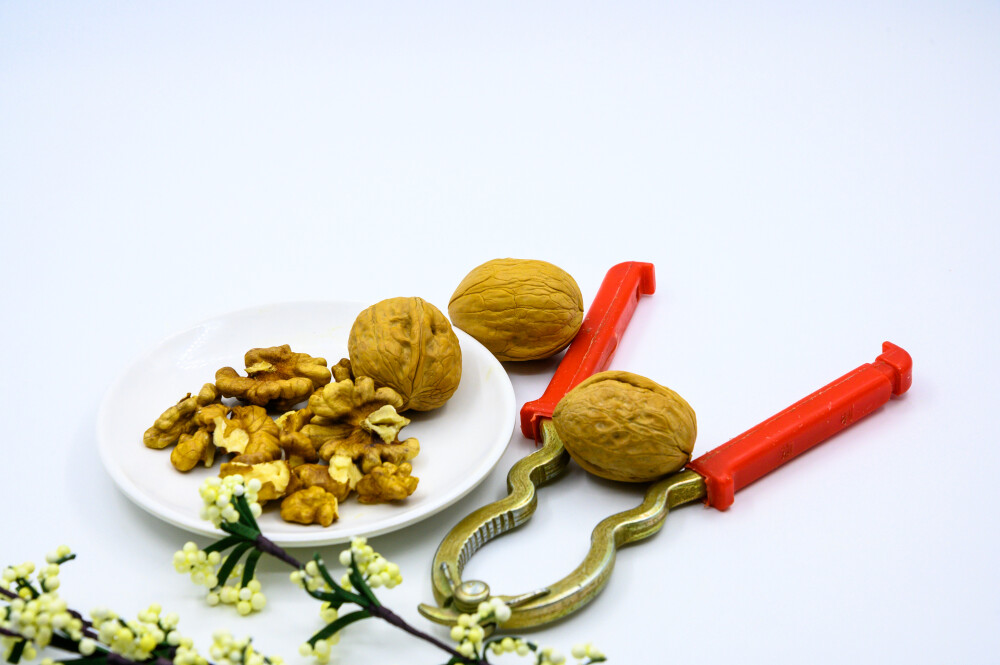 食品 食物 植物 果实 成熟的 特写 绿色食品 美味 零食 坚果 干果 核桃 核桃仁 膳食纤维 小吃 益智 亚洲 健康食物 有机食品 膳食 养生 滋补 营养 食材 生活方式 健康的 白色背景 白瓷盘 干果钳 简单背景
