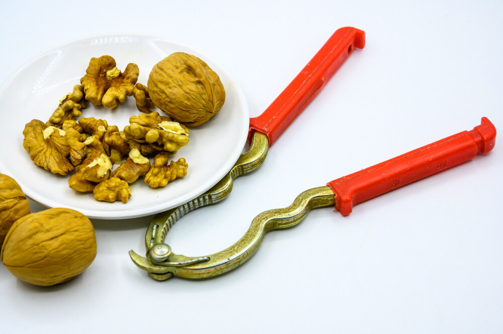 食品 食物 植物 果实 成熟的 特写 绿色食品 美味 零食 坚果 干果 核桃 核桃仁 膳食纤维 小吃 益智 亚洲 健康食物 有机食品 膳食 养生 滋补 营养 食材 生活方式 健康的 白色背景 白瓷盘 干果钳 简单背景
