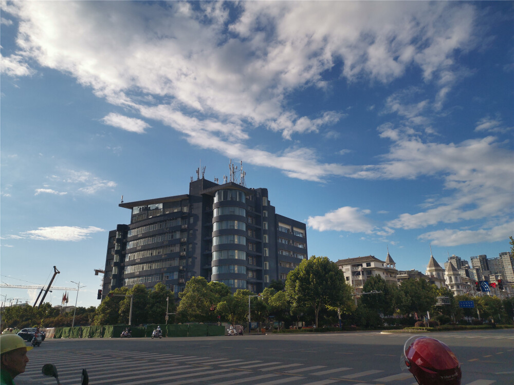 8月13日，天气是那么晴朗，天空是那么蔚蓝，白云也是千姿百态，再加上行色匆匆的人群、川流不息的车辆，宏伟壮观的高楼大厦，形成了一幅幅美丽的画卷。（摄/肖勇）