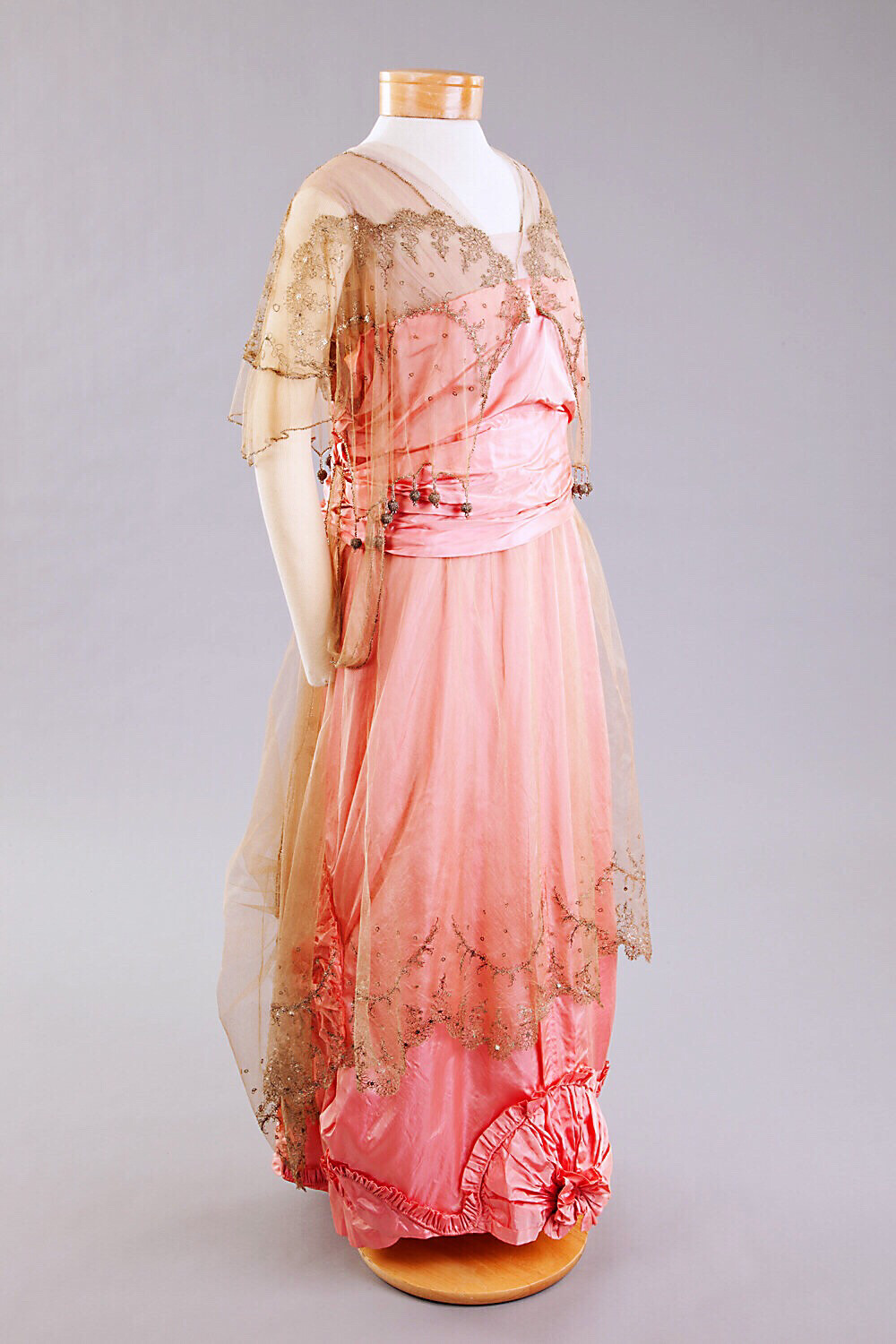 1912-17 粉色丝缎晚礼服 外罩网状织物 有水晶珠子组成的花朵图案 上衣边缘垂下小球状垂饰 裙摆褶边组成玫瑰花结 