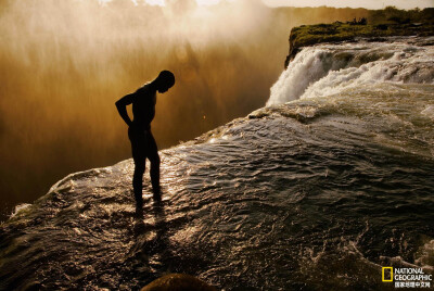 维多利亚瀑布
赞比亚的维多利亚瀑布（Victoria Falls），一位游泳者站在一个隐藏的游泳池的边缘——河床岩石中有一个2.4米左右深的凹陷，只有在赞比西河水位较低时才能进入。摄影：ANNIE GRIFFITHS