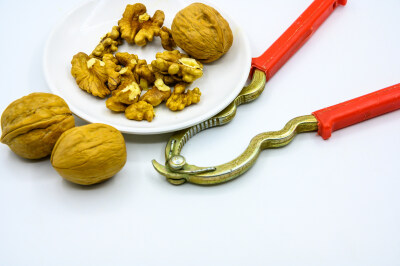 食品 食物 植物 果实 成熟的 特写 绿色食品 美味 零食 坚果 干果 核桃 核桃仁 膳食纤维 小吃 益智 亚洲 健康食物 有机食品 膳食 养生 滋补 营养 食材 生活方式 健康的 白色背景 白瓷盘 干果钳 简单背景
