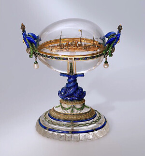 斯丹达特游艇复活节彩蛋  The “Standart” Yacht Easter Egg 是 法贝热 Fabergé1909 年制作 尼古拉二世送给亚历山德拉·费奥多罗夫娜皇后的礼物1909. 是沙皇皇家游艇的微缩复制品，彩蛋安装在黄金支承架上，边缘上有1909年的题词。金环带内是珐琅镶嵌的绿叶，有小钻石组成的线条围绕彩蛋的周边。下半部的彩蛋装饰有一个垂直的金带镶嵌设计，彩蛋两侧栖息着由青金石雕刻的带有皇冕的雄鹰，每只鹰的胸前挂有梨形珍珠。水晶彩蛋内是一个黄金制作的游艇斯丹达特的副本。该游艇是亚历山大三世时的游艇，制作于1895年，全长为116米长，是当时世界上最大的游艇。