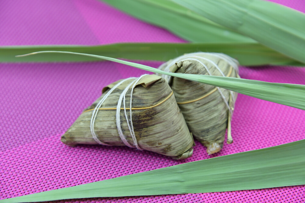 粽子 端午节 煮熟的 食物 食品 美味 甜的 中国食品 传统节日 中国节日 中国传统文化 中国传统美食 屈原 黏 软 江米 三角形 包装 叶子 竹叶 苇叶 静物 绿色 青色 糯米 黑色背景 米 大米 白米 粉色桌布 枣 大枣 红枣 干枣 红色 滋补 绿叶 竹叶
