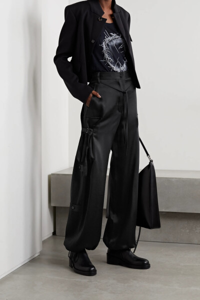 Ann Demeulemeester 这款工装裤诞生于意大利，亮泽的黑色缎布材质为原本休闲的版型平添了精致感和潮酷度。裤脚抽绳可将宽松的裤腿加以收束，背面的纽扣缀饰进一步体现了设计师的匠心巧思。别忘了系上细腰带，让穿着…