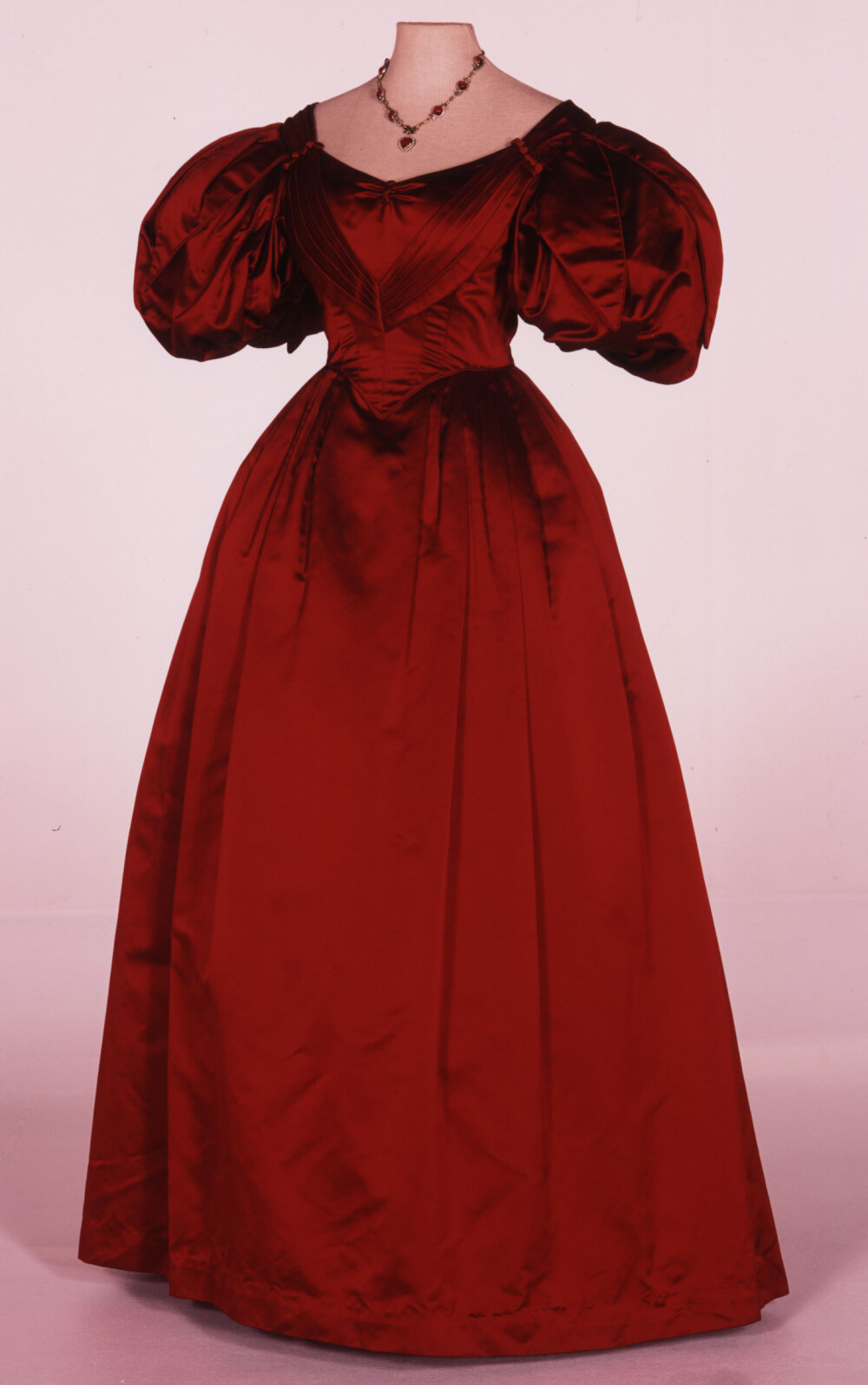 丽芙·泰勒在电影《奥涅金》中穿的一件晚装，典型的1830年代泡泡袖裙子，通身美丽的深红色缎子，优雅又夺目。虽然这件衣服用料纯粹，没有外加其他材质，但领口的褶边和袖子上的花叶形装饰仍让整件衣服不失丰富，且年代感极佳。设计师John Bright是英国戏服界以考究闻名的老前辈，他和搭档珍妮·碧万合作过《看得见风景的房间》、《霍华德庄园》等名作，自己也有《金碗》等优秀的独立作品。