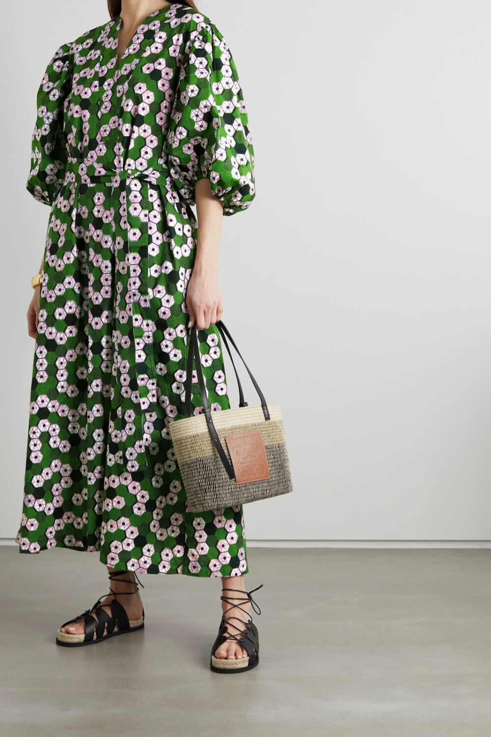Odile Jacobs 在母亲的带领下走进了非洲特色打蜡纯棉的世界，在成立同名品牌后，她更是将这一面料奉为品牌的核心元素。这款连衣裙以手工精心制成，灵活系带强调出优雅的裹身设计，绿色与粉色几何感印花热烈而鲜艳。只需搭配一双凉鞋与编织手提包，你便可以完成整套造型，以时髦姿态迎接夏日。