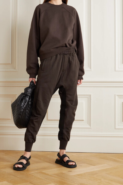 Haider Ackermann 这款 “Moonshape” 休闲裤以柔软的纯棉平纹布精心制成，膝盖设有罗纹拼接料，裤腿内侧的竖条纹则在视觉上收缩了裤型，营造出灯笼裤般的柔和弧度。收窄的裤脚与运动裤或凉鞋搭配皆宜。