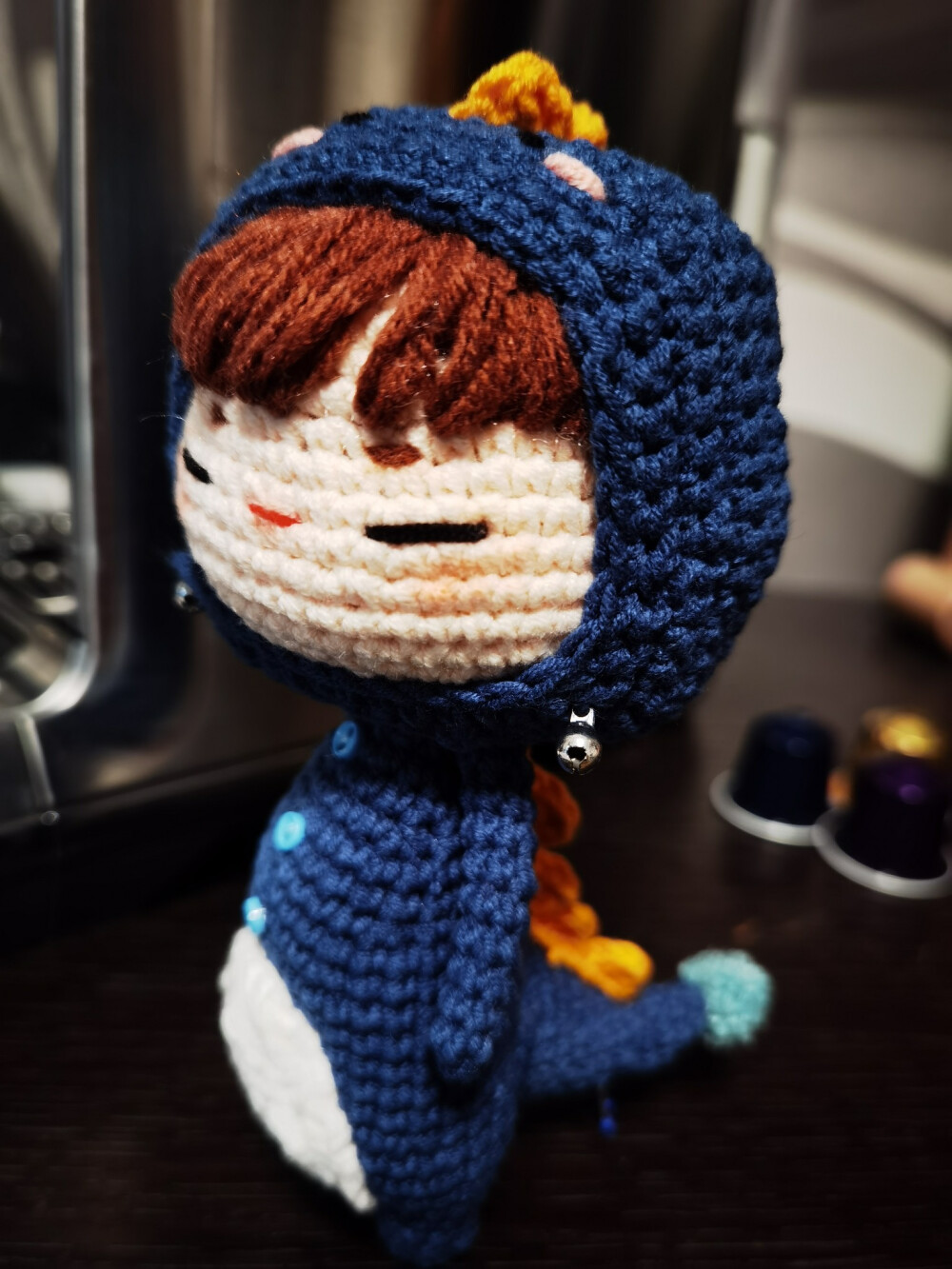 复古蓝+胡萝卜橙黄，一只温柔傲娇的小恐龙娃娃，喜欢蹲在咖啡机和黑色电脑旁边。