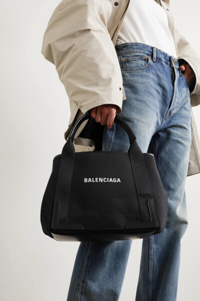 Balenciaga 这款 “S Cabas” 手提包诞生于意大利，是以挺括的帆布制成，其上印有醒目的白色品牌标志。光滑皮革边饰加固了方正的包身，内置小袋则可将你的口红和手机收纳稳妥。